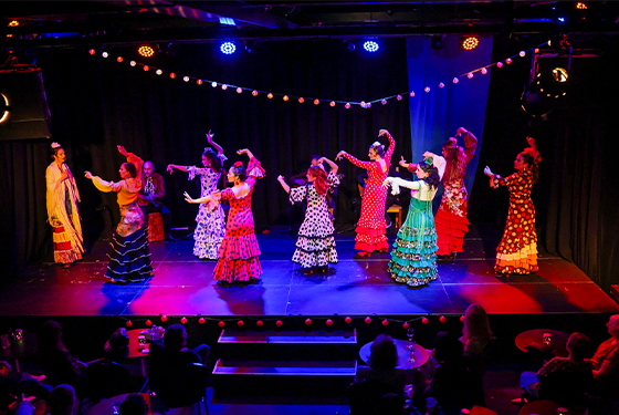 Group of women dancing on stage wearing colourful dresses