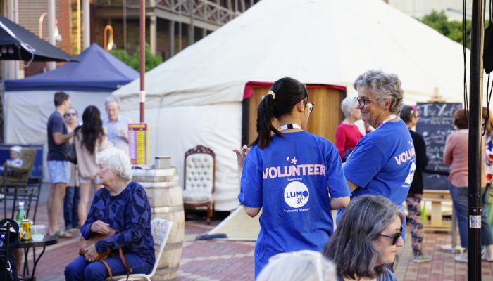 Two volunteers wearing blue shirts with their back to the camera standing up