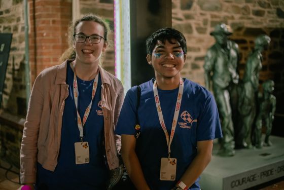Two volunteers wearing blue tshirts smiling at the camera at night