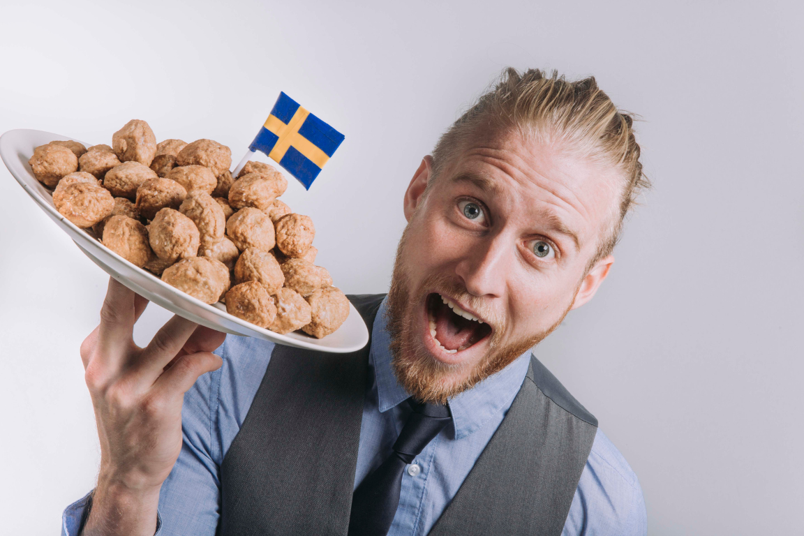 Man in a suit holding a plate of Swedish meatballs