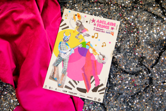 2024 Adelaide Fringe Guide lying on a piece of pink and silver sequined fabric