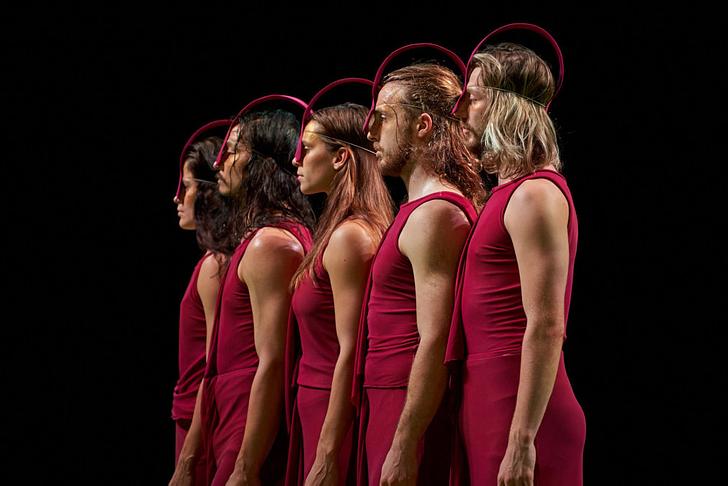 A group of dancers stand in a line looking out to an audience 