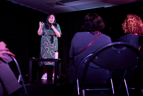 Comedian Jennifer Wong is performing on stage with an audience watching. 