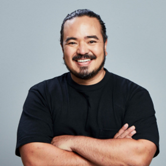 Adam Liaw standing looking at the camera in a black tshirt with his arms folded