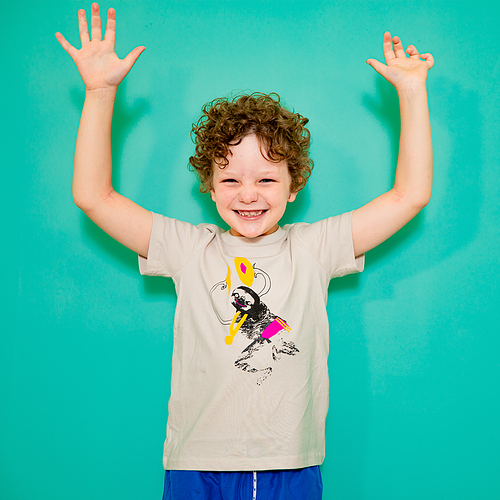 A child wears a t-shirt with a sloth on it. He is waving his hands in the air. 