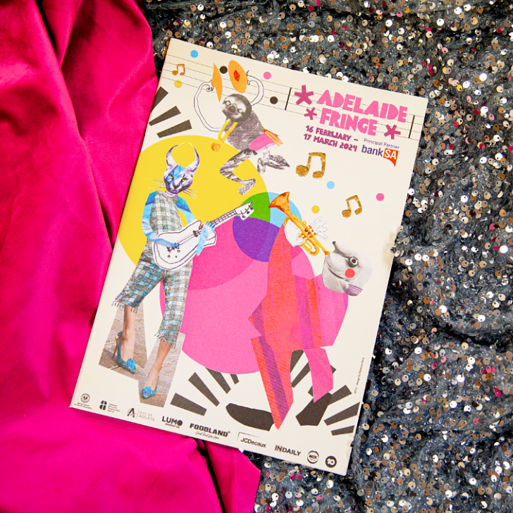 2024 Adelaide Fringe Guide lying on a piece of pink and silver sequined fabric 