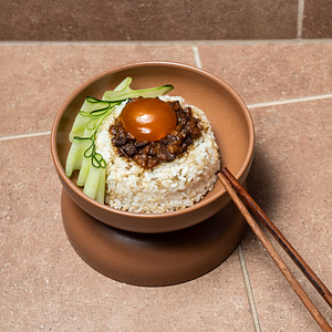 Close up of a bowl of rice and cucumber in a terracotta bowl on tiles
