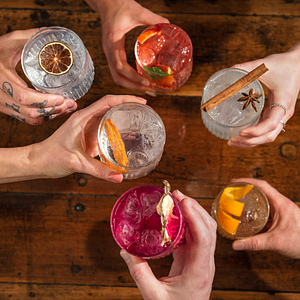 Six people holding a range of colourful drinks cheersing