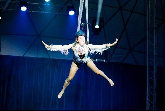 A performer is swinging above the stage imitating a bird.  